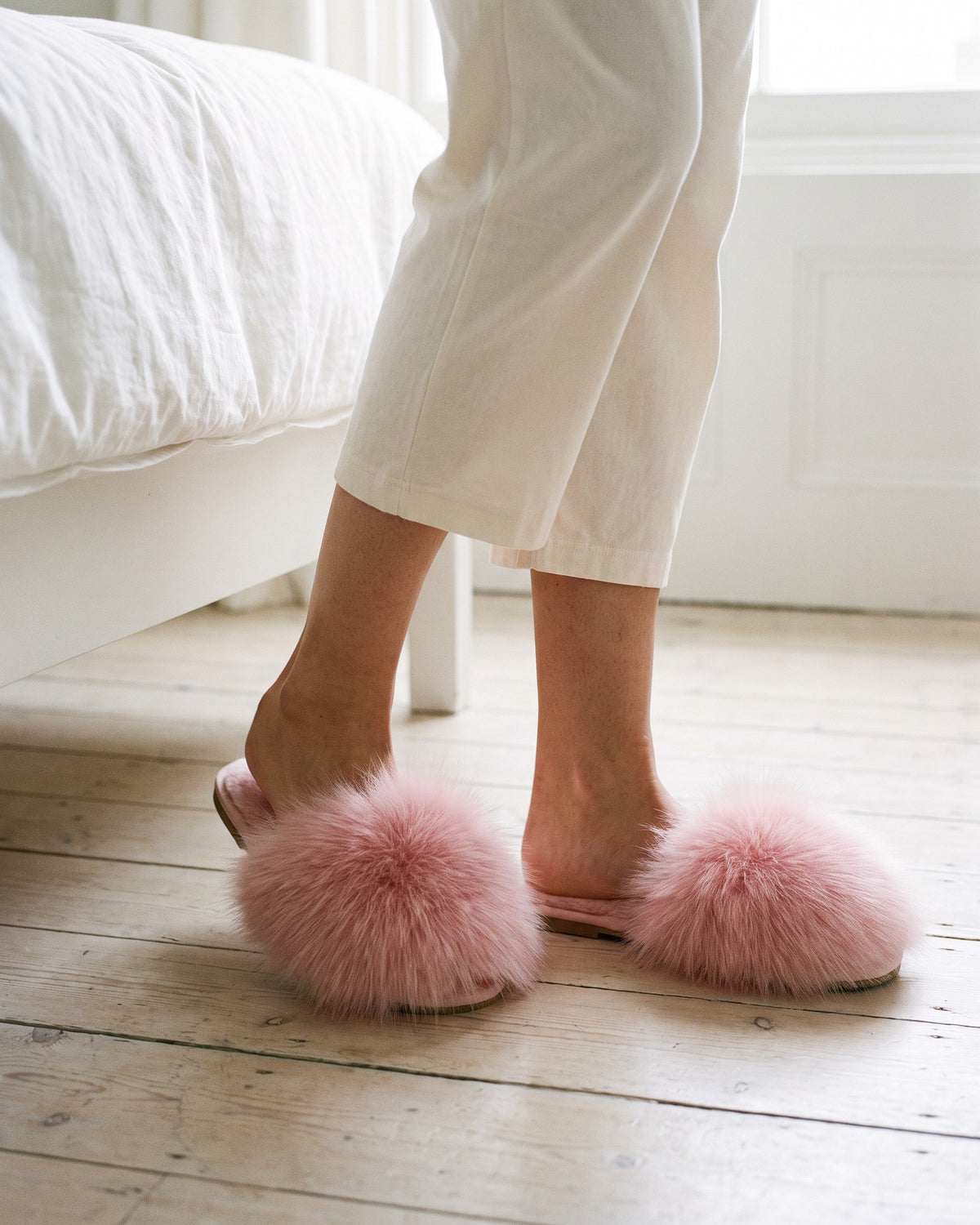Pink pom pom slippers worn with cream pyjamas