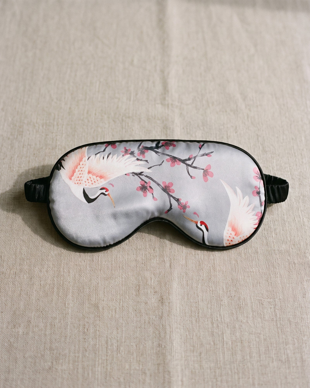 Night Owl Pyjamas Sakura Satin Eye Mask in grey, shown as a bedtime accessory