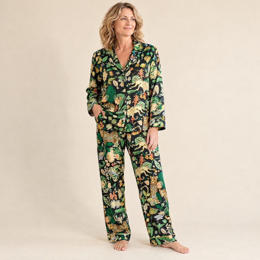 Woman wearing the Black Jungle Leopard long pyjama set in black satin with golden piping, full-length front view