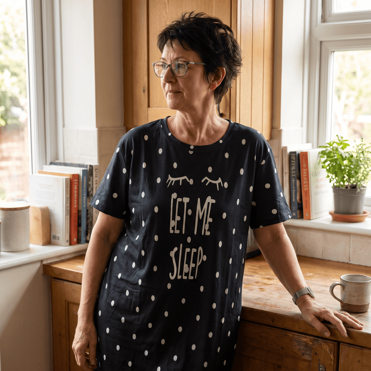 Woman wearing a black polka dot Night Owl Pyjamas nightdress with 'Let Me Sleep' text.