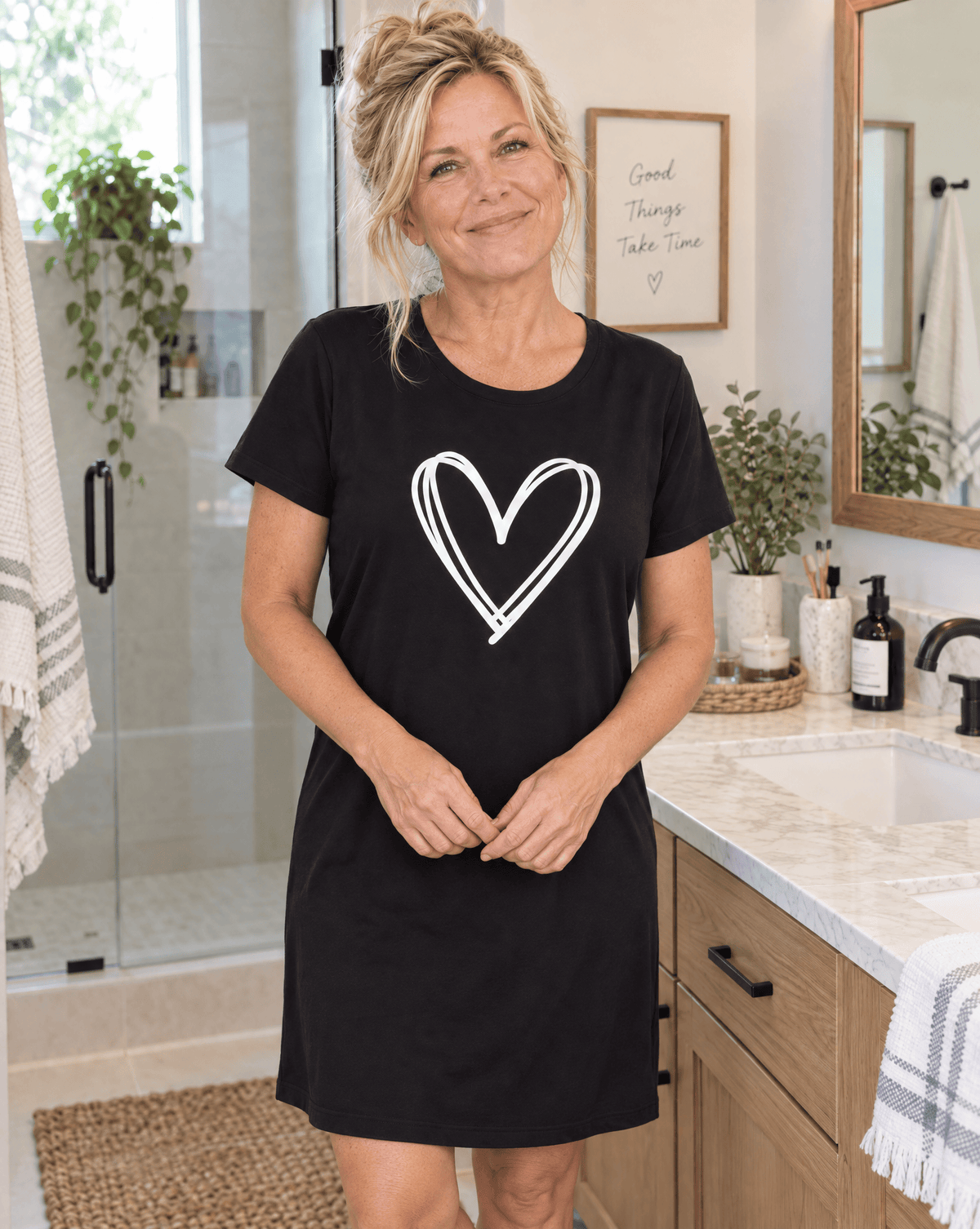 Woman wearing a Night Owl Pyjamas black lightweight nightdress with a white heart design.