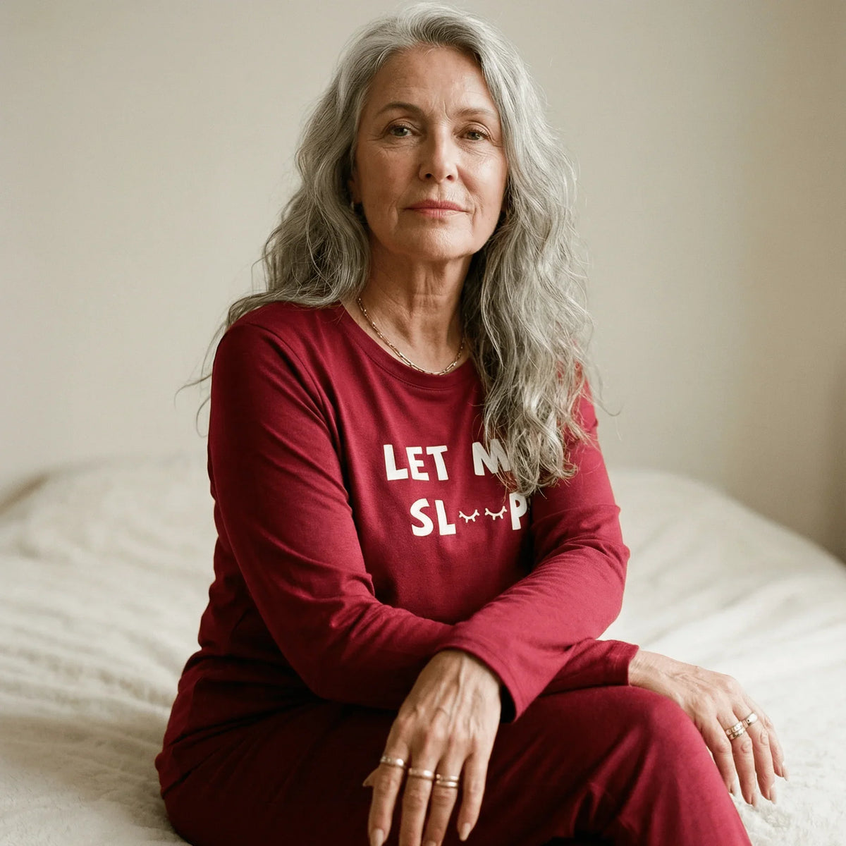 Woman with grey hair wearing a red Night Owl Pyjamas lightweight set with 'Let Me Sleep' text.