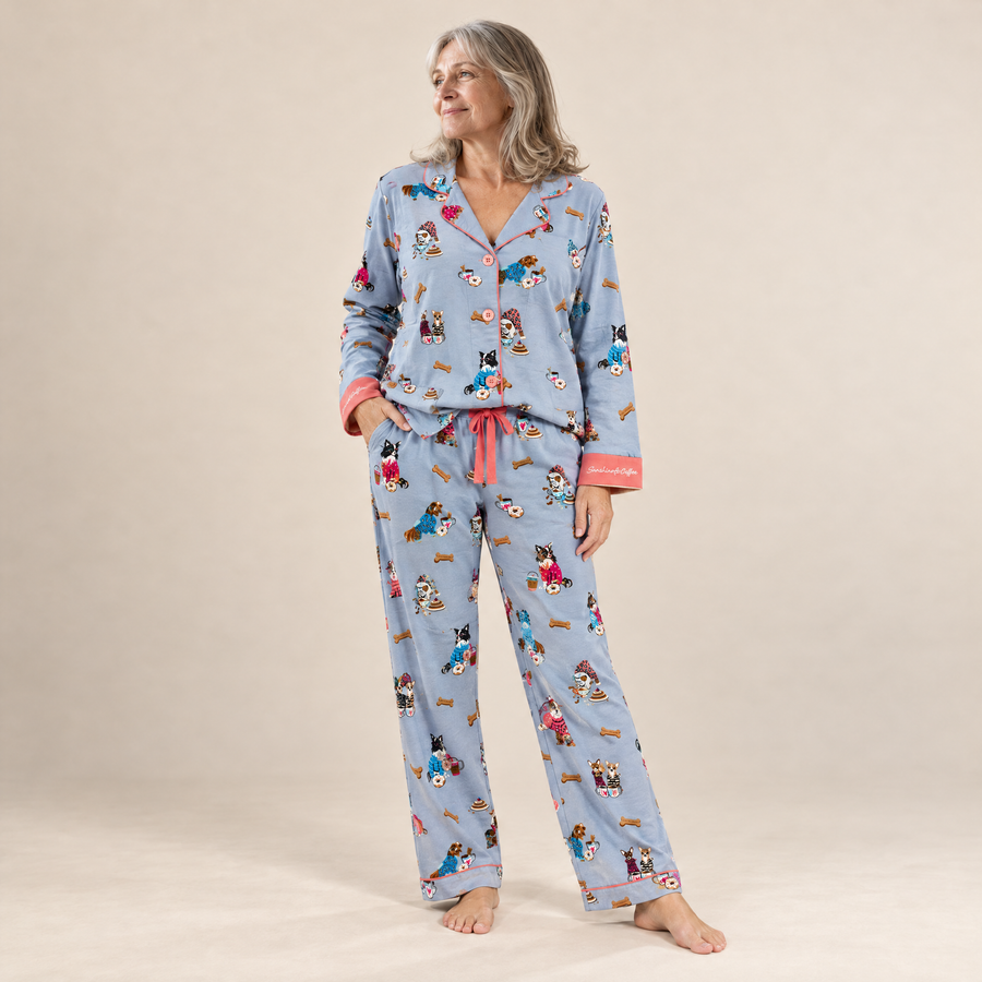 Woman wearing light blue cotton flannel pyjamas with a print of dogs in coats, front view