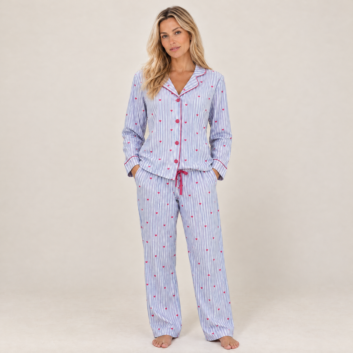 Blonde woman relaxing in blue stripes and pink hearts cotton flannel pyjamas, full-length view